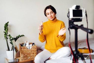 Genç esmer kız güzellik blogcusu kamerada nasıl antiseptik kullanılacağını gösteriyor. Blog çekmenin konsepti. Güzellik ve cilt bakımı.