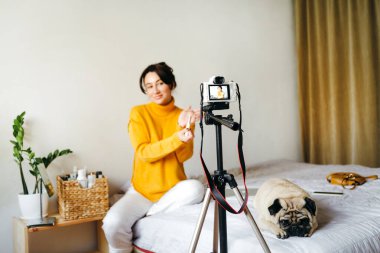 Genç esmer kız güzellik blogcusu kamerada fırça gösteriyor. Blog çekmenin konsepti. Güzellik ve cilt bakımı.