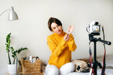 Genç esmer kız güzellik blogcusu kamerada fırçayı nasıl kullanacağını gösteriyor. Blog çekmenin konsepti. Güzellik ve cilt bakımı.