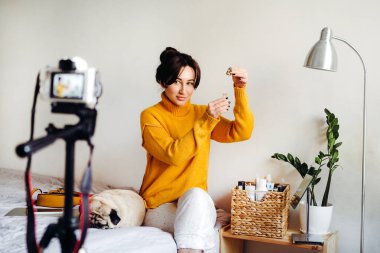 Genç esmer kız güzellik blogcusu kamerada cilt bakımı için nasıl serum yapılacağını gösteriyor. Blog çekmenin konsepti. Güzellik ve cilt bakımı.
