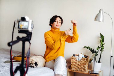 Genç esmer kız güzellik blogcusu kamerada cilt bakımı için nasıl serum yapılacağını gösteriyor. Blog çekmenin konsepti. Güzellik ve cilt bakımı.