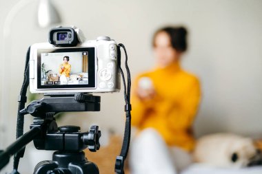Genç esmer kız güzellik blogcusu kamerada cilt bakımı için nasıl sis yapılacağını gösteriyor. Blog çekmenin konsepti. Güzellik ve cilt bakımı.