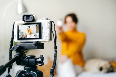 Genç esmer kız güzellik blogcusu kamerada cilt bakımı için nasıl sis yapılacağını gösteriyor. Blog çekmenin konsepti. Güzellik ve cilt bakımı.