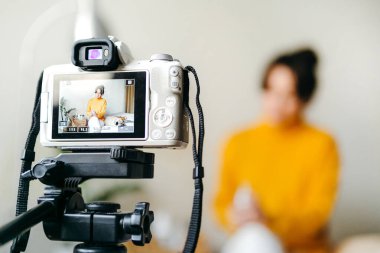 Genç esmer kız güzellik blogcusu kamerada cilt bakımı için nasıl sis yapılacağını gösteriyor. Blog çekmenin konsepti. Güzellik ve cilt bakımı.