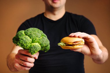 Sağlıklı yemek brokoli ve sağlıksız abur cubur hamburu arasında seçim yapmak..