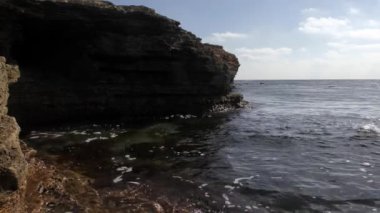 Taş sahil, berrak Denizi, küçük dalgalar.