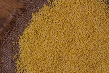 Darı. Darı kabuğu çıkarılmış tane ahşap arka plan ve çuval bezi üstten görünüm üzerinde