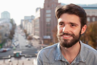 Handsome bearded man enjoying warm day at the city clipart