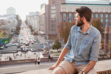 Handsome bearded man enjoying warm day at the city clipart
