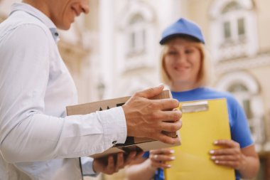 Şehir sokaklarında mavi üniformalı, dost canlısı bir teslimatçı kadın.