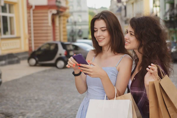 Női barátok használata okos telefon séta közben város utcáin — Stock Fotó