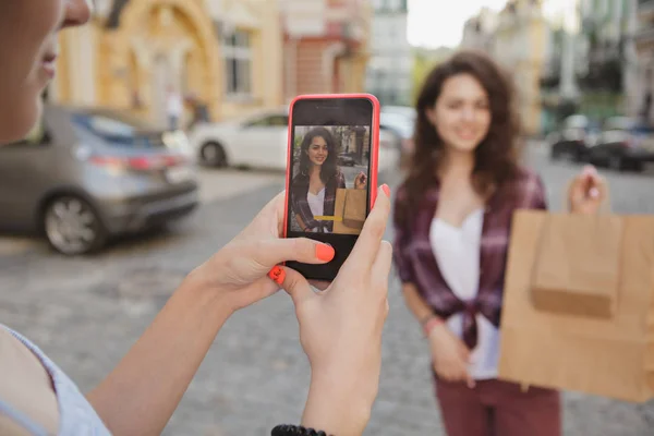 Female friends using smart phone while walking city streets