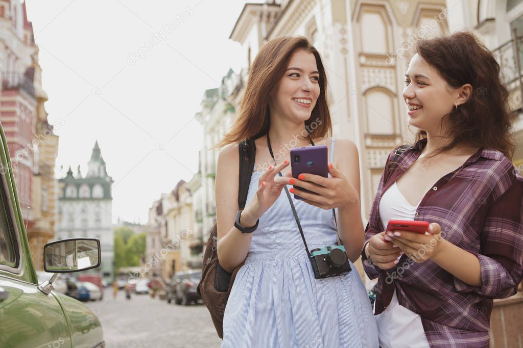 Young female friends enjoying traveling together, using map in t