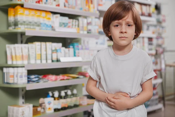 Маленький больной мальчик в аптеке — стоковое фото