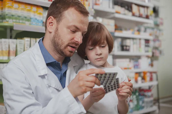 Mature male pharmacist helping little boy at drugstore — Stock Photo, Image