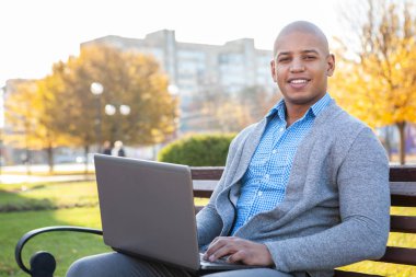 Yakışıklı Afrikalı iş adamı laptopuyla dışarıda çalışıyor.