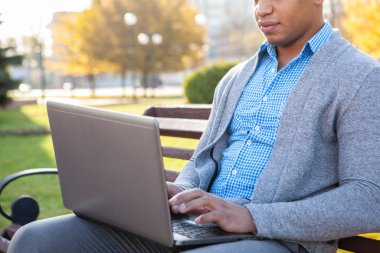 Yakışıklı Afrikalı iş adamı laptopuyla dışarıda çalışıyor.