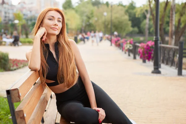 Güzel, fit bir kadın sabah antrenmanından sonra dışarıda dinleniyor.