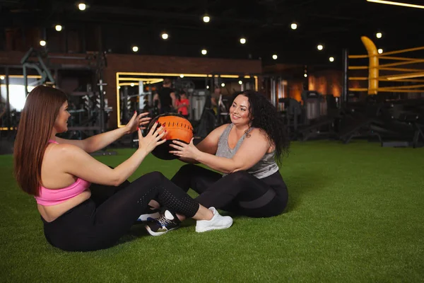 Spor salonunda birlikte egzersiz yapan güzel ve iri yarı sporcu kadınlar.