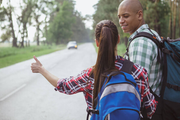 Charming multiracial couple hitchhiking together