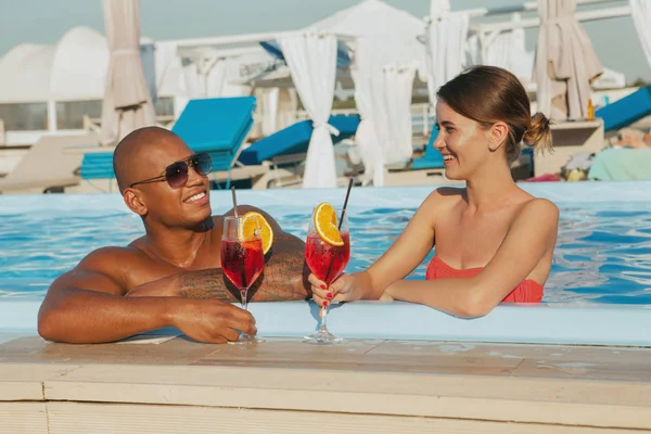 Glad multietniskt par koppla av tillsammans vid poolen — Stockfoto