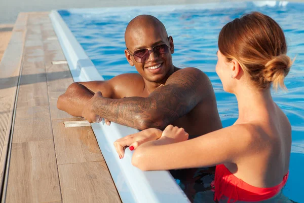 Glad multietniskt par koppla av tillsammans vid poolen — Stockfoto