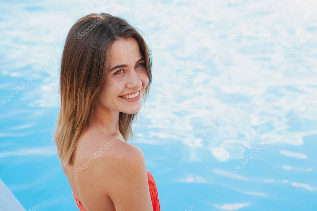 Beautiful happy woman resting at the poolside