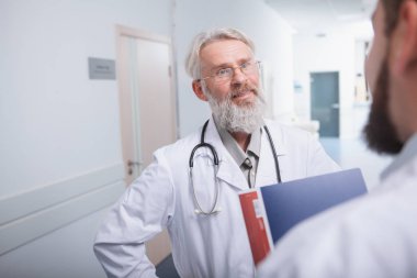 Kıdemli erkek doktor hastanede bir meslektaşımla konuşuyor.