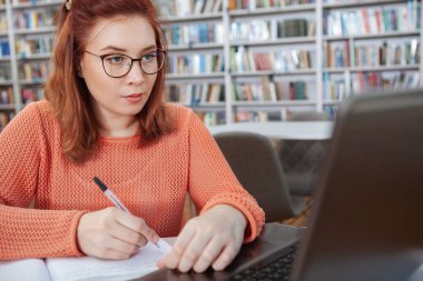Kütüphanede bilgisayar kullanan kız öğrenci