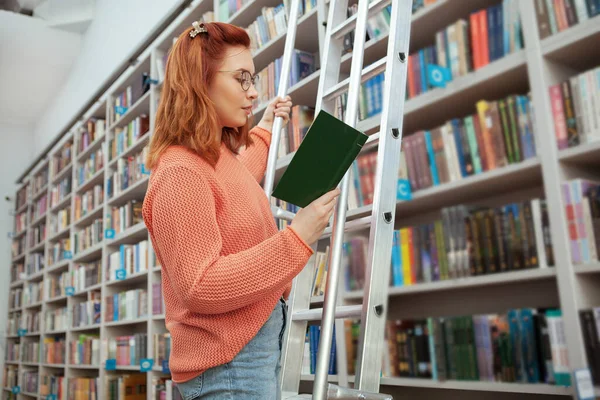 Молода жінка читає в бібліотеці — стокове фото
