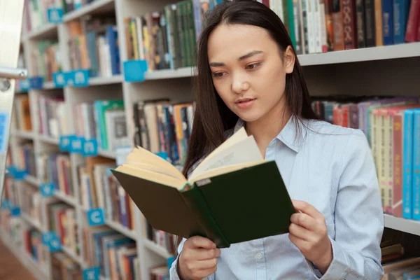 Vonzó ázsiai nő olvas a könyvtárban — Stock Fotó