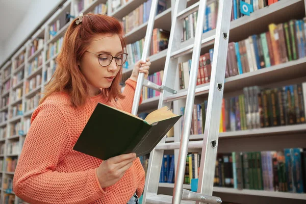 Молода жінка читає в бібліотеці — стокове фото