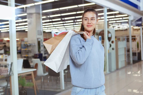 幸せな若い女性の笑顔 離れて明るく見て ショッピングバッグをモールで運ぶ — ストック写真