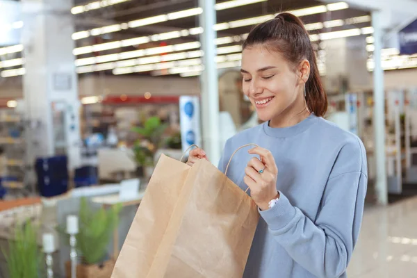 若い魅力的な女性は興奮して 彼女のショッピングバッグを開きます 幸せな女性の顧客見て内側彼女のショッピングバッグ — ストック写真