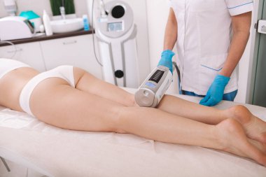 Profesyonel bir kozmetolojistin kadın bir müşteriye sonosfer terapi makinesi kullanırken görüntüsü kesilmiş.