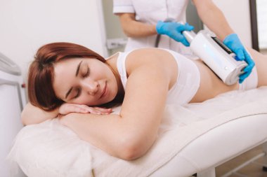 Lovely young woman enjoying  skin tightening massage by beautician