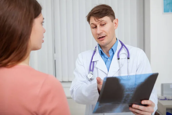 有经验的男医生向在办公室工作的女病人解释X光扫描结果 — 图库照片