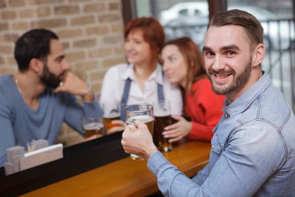 Schöner Bärtiger Mann Lächelt Die Kamera Trinkt Bier Mit Freunden — Stockfoto