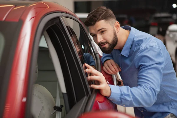 Guapo Barbudo Joven Examinando Nuevo Coche Moderno Concesionario Espacio Copia — Foto de Stock