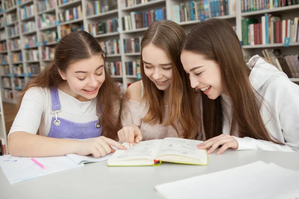 Wesołe Nastolatki Śmieją Się Czytając Razem Książkę Szkolnej Bibliotece — Zdjęcie stockowe