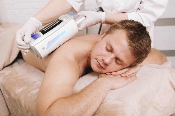 Relaxed man enjoying full body massage with massager by professional therapist