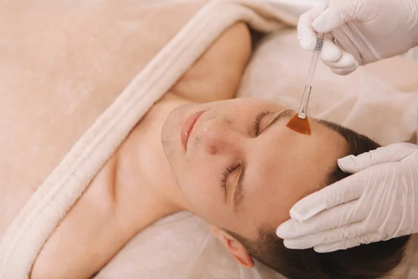 Close up of a cosmetologist applying moisturizer on the skin of male client