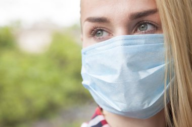 Tıbbi koruyucu maske takmış bir kadının bakışlarını yakından kesmiş. Bağışıklık sistemi, koronavirüs konsepti