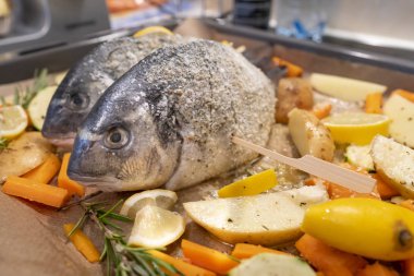 Fırında pişirilmiş sebzelerin üzerine çipura dökülmüş.