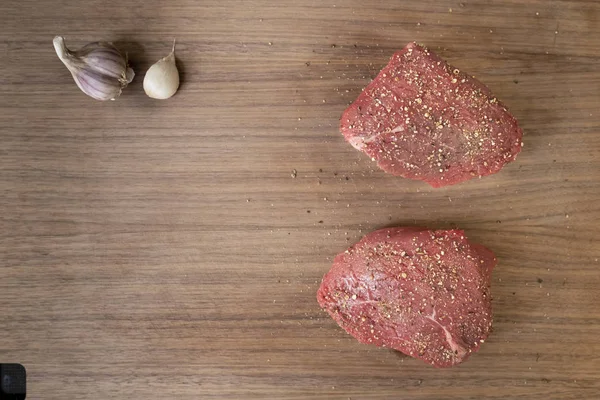 Два сырых перец говяжий стейк на темной деревянной доске резки с га — стоковое фото