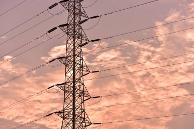 Gün batımında güzel gökyüzü ile yüksek güçlü enerji nakil direkleri.