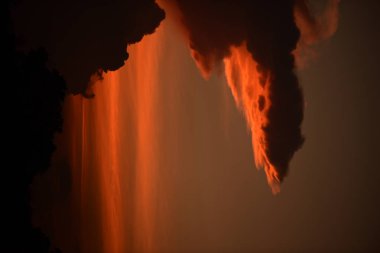 Dağın zirvesine günbatımı manzara. Turuncu-kırmızı bulutun turuncu gökyüzü ve üst üste gelen dağ manzaraları vardır.