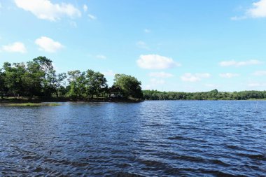 Göl Manzaralı orada ağaçlarıyla güzel bulutlar ve Yeşil dağlar vardır.