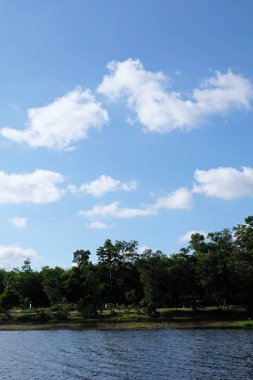 Göl Manzaralı orada ağaçlarıyla güzel bulutlar ve Yeşil dağlar vardır.