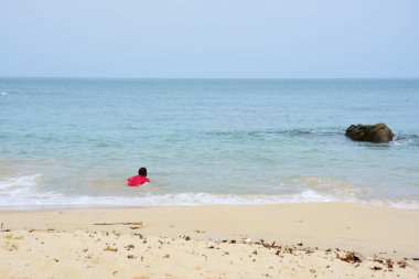 Güzel bir plaj, beyaz dalgalar, kayalar ve balıkçı tekneleri, esinti, güneş parlak gün ışığında beyaz kum plaj.